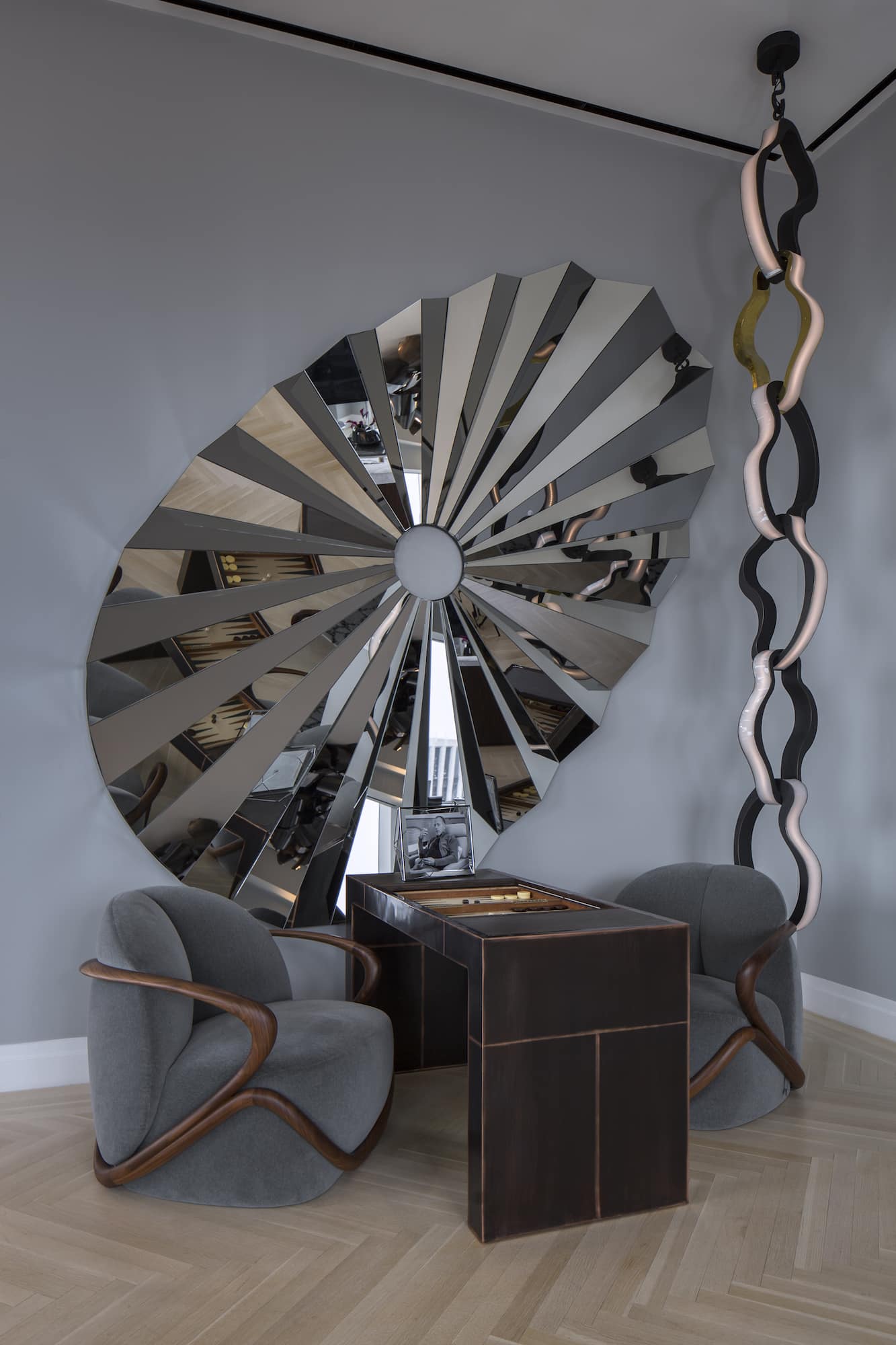 This niche of the Gulla Jónsdóttir-designed apartment has a Giorgetti Hug chairs pulled up to a Mauro Mori backgammon table. The custom mirror and limited-edition Link light are by Jónsdóttir.