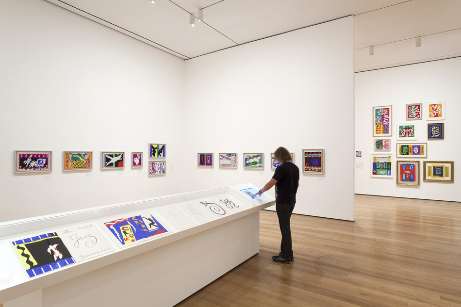 A display case contains pages from the artist’s 1947 illstrated book, Jazz, and the digital display lets visitors virtually flip through the entire book. Photo by Jonathan Muzikar © 2014/MoMA