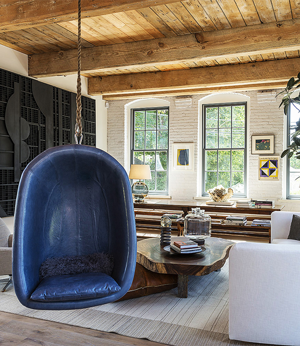 In Huniford’s living room, a blue leather chair is suspended from the ceiling and a black wood Louise Nevelson sculpture hangs on the wall on left. Photo by Paul Domzal, Edge Media