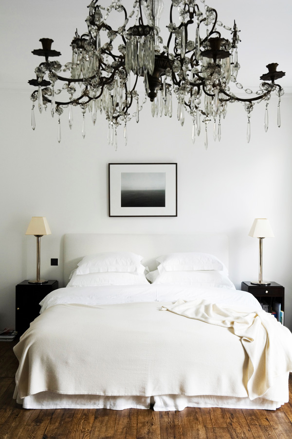 A grand chandelier adds glamour to the otherwise understated bedroom of a London house.