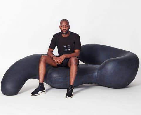 Rich Mnisi, designer, sits on a chaise of his own design