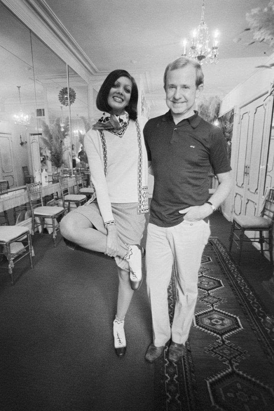 Designer Adolfo auf einem Foto aus dem Jahr 1979 mit einem Model, das eines seiner Ensembles trägt