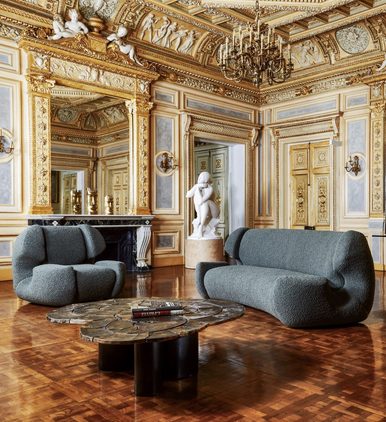 Die modernen Formen des Sessels und Sofas „Colisée“ von Studio Glustin setzen einen zeitgemäßen Kontrapunkt zum opulenten Dekor im Pariser Ausstellungsraum Palais Vivienne. 