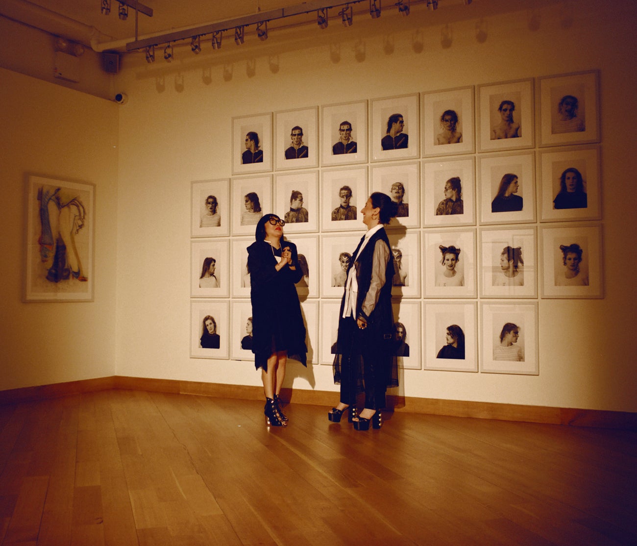 Aimée Chan-Lindquist (links), Leiterin der Abteilung für externe Angelegenheiten des Leslie-Lohman Museums, und die Geschäftsführerin Alyssa Nitchun stehen gemeinsam im Museum vor Lorenza Böttners 30 Porträts umfassenden Installation „Face Art“ aus dem Jahr 1983.