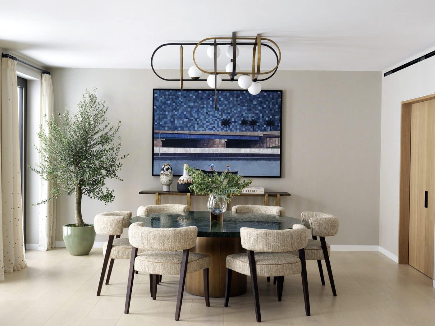 La salle à manger du logement de Londres comporte un lustre en laiton et en bronze ainsi qu'une table avec un plateau texturé et un pied en laque et en laiton, tous deux conçus par Natalia Miyar.