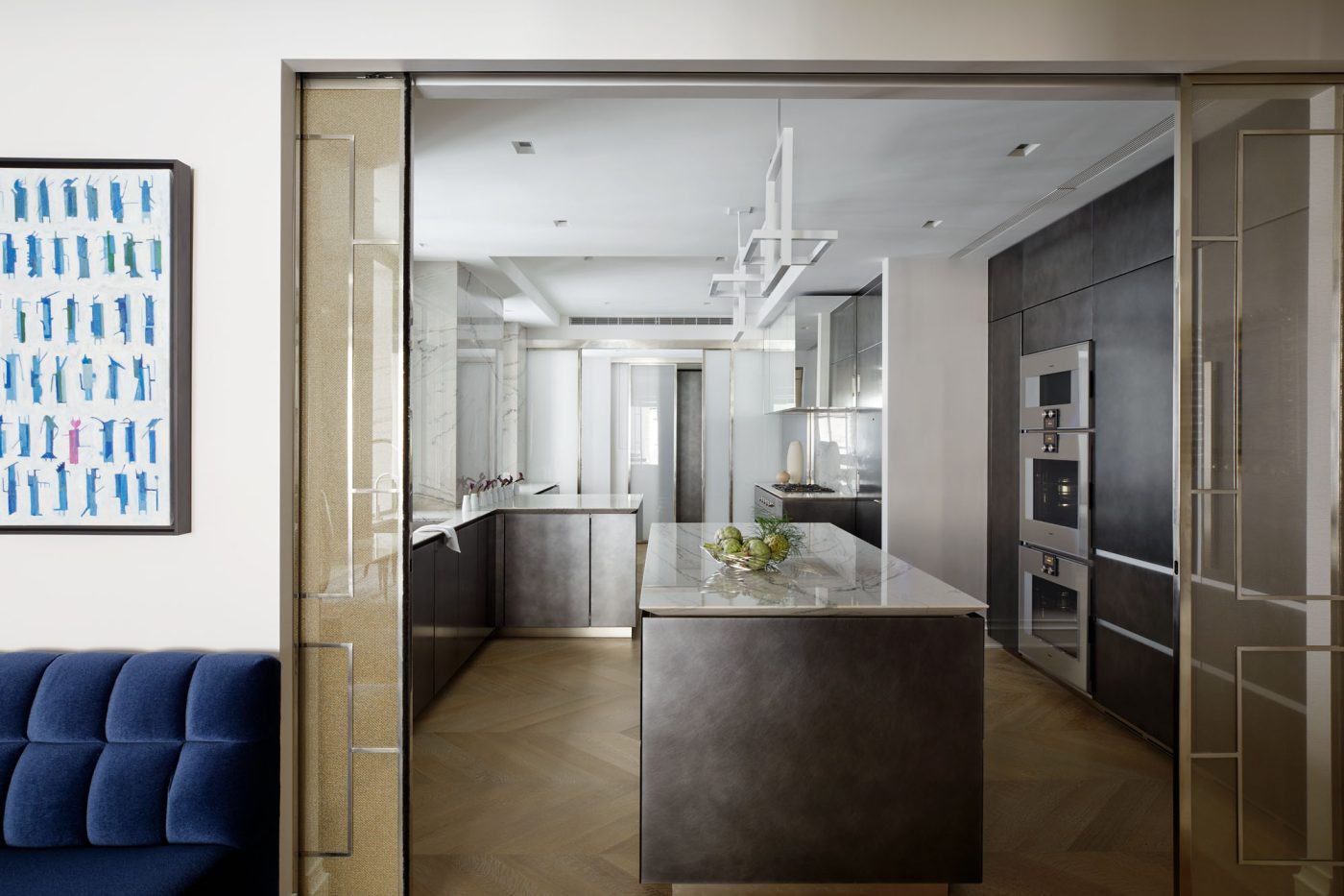 Vue de la cuisine argentée derrière les portes coulissantes de l'appartement de la Cinquième Avenue à Manhattan conçu par David Kleinberg.
