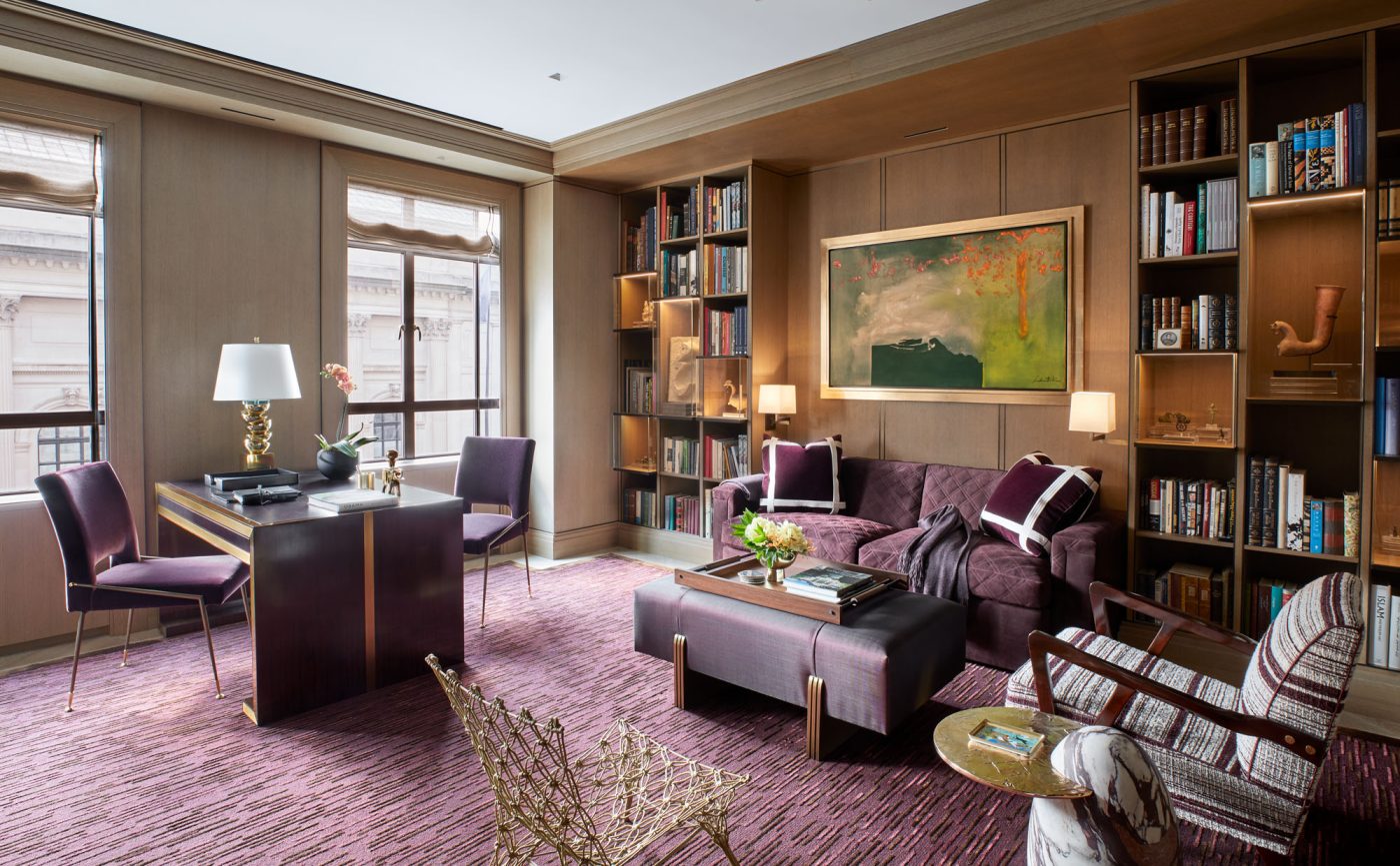 Bibliothèque en bois avec des accents bordeaux et un tableau d'Helen Frankenthaler dans un appartement de la Cinquième Avenue à Manhattan, conçu par David Kleinberg.