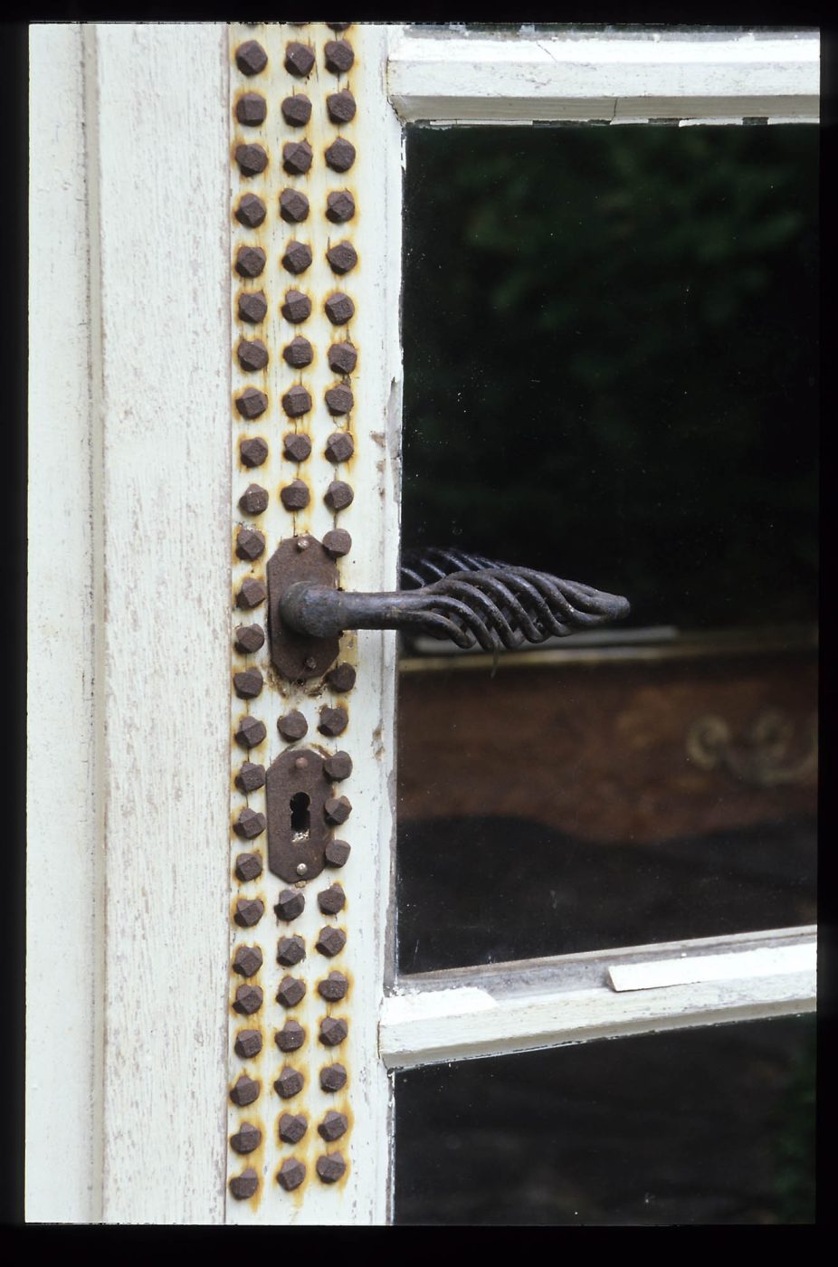 Une porte avec un motif de tête de clou au-dessus et au-dessous de la poignée de la porte dans la maison de Jean Royère en Bretagne