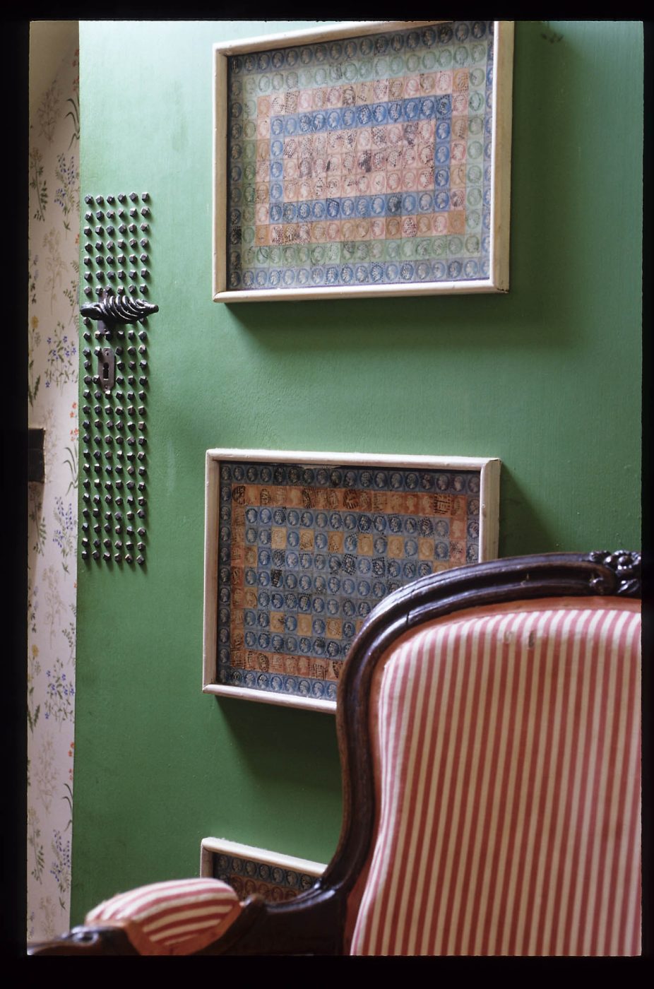 Un collage de timbres encadré est accroché à la porte d'une chambre d'amis dans la maison de Jean Royère en Bretagne.