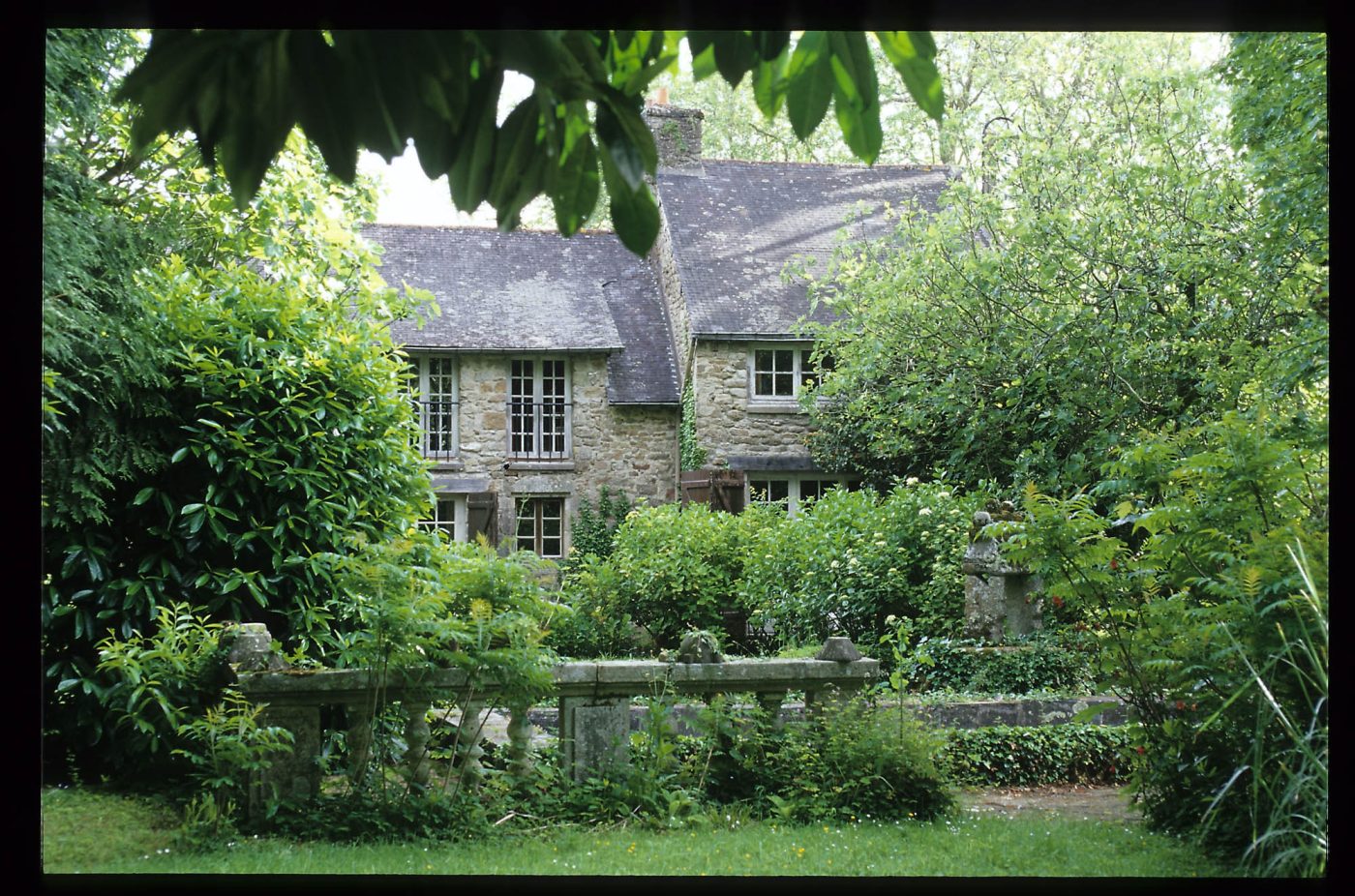 Un bâtiment en pierre entouré de verdure sur le domaine de Jean Royère en Bretagne