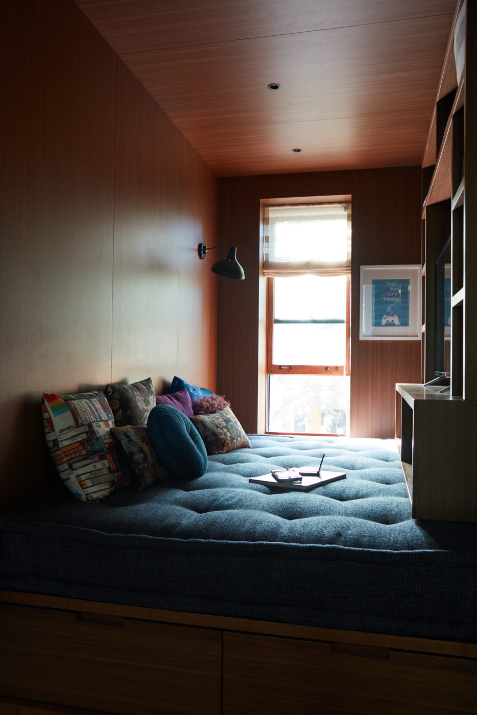 En dehors des chambres des garçons, les concepteurs ont transformé le petit espace situé au bout du hall d'escalier en un lieu de divertissement confortable, où un lit de jour en peluche garni de coussins se glisse dans l'alcôve lambrissée de noyer, ainsi que des armoires pour la télévision et l'équipement de jeu.