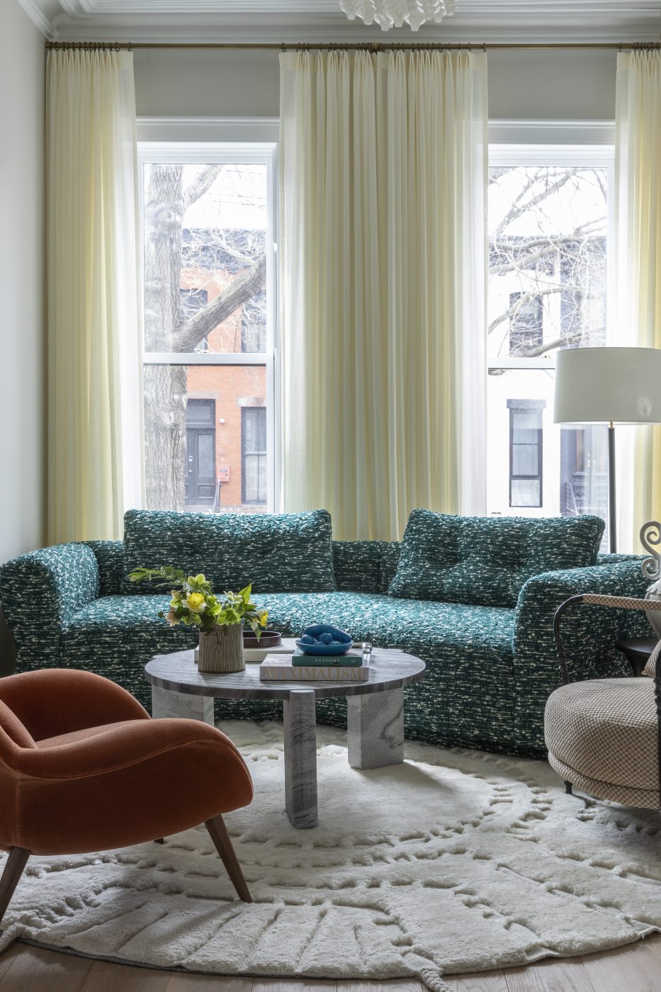 Dans le salon avant, un canapé sur mesure s'enroule autour d'une table basse en pierre, rejoint par une chaise longue en mohair de Space Copenhagen, tandis qu'un lustre Kalmar Tulipan des années 1960 apporte une touche vintage.